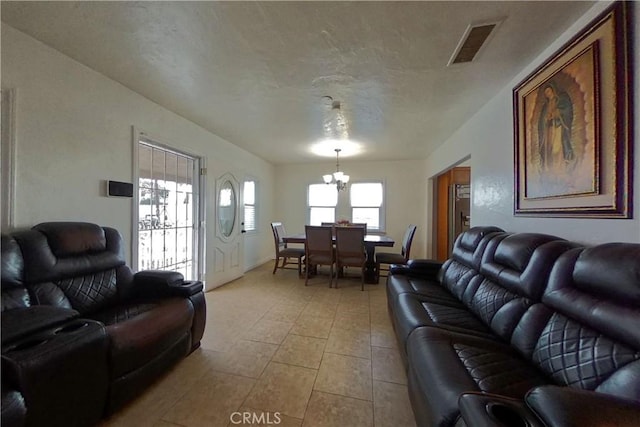 living area with visible vents, a chandelier, a textured ceiling, and light tile patterned flooring