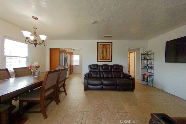 living area featuring visible vents, a notable chandelier, and a textured ceiling