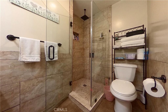 full bath with toilet, a shower stall, and tile walls