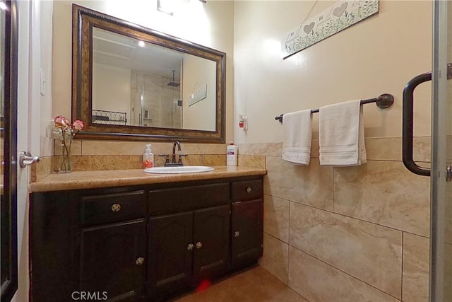 full bathroom with wainscoting, walk in shower, tile walls, and vanity