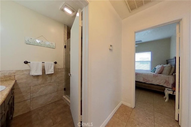 ensuite bathroom with tile walls, visible vents, a shower stall, and tile patterned floors