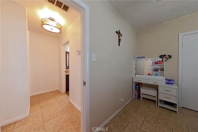 hallway with baseboards, visible vents, and tile patterned flooring