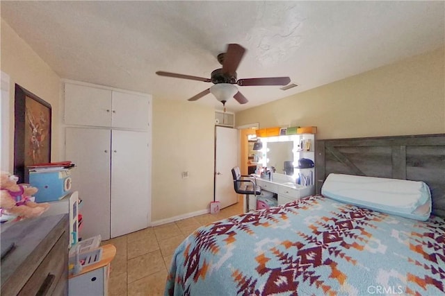 bedroom with light tile patterned floors, a closet, visible vents, ceiling fan, and baseboards