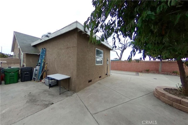 view of home's exterior featuring crawl space, fence, a patio, and stucco siding