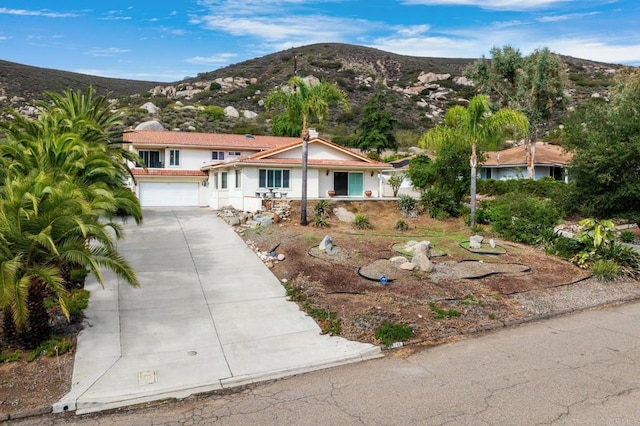 view of front facade featuring a mountain view, a garage, and concrete driveway