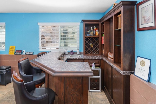 bar with a sink, stone finish flooring, and a bar