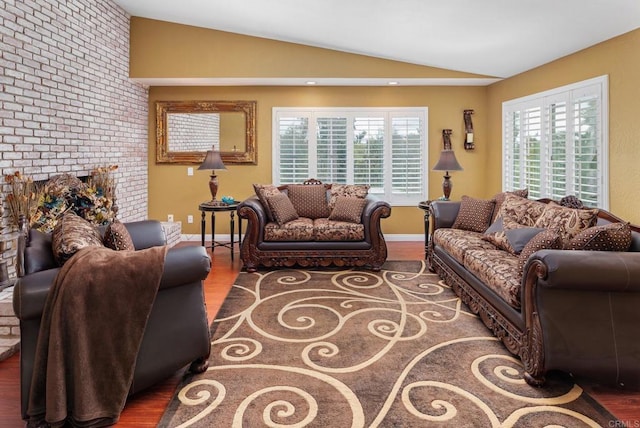 living area with baseboards, wood finished floors, a fireplace, and vaulted ceiling