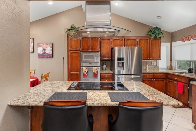 kitchen with lofted ceiling, a sink, appliances with stainless steel finishes, a kitchen bar, and island range hood