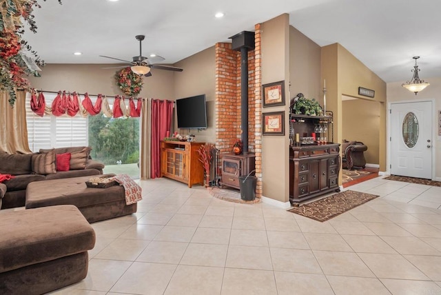 living area featuring vaulted ceiling, a wood stove, light tile patterned floors, and a ceiling fan