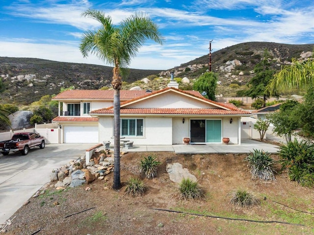 view of front of home featuring fence, stucco siding, concrete driveway, a tiled roof, and a mountain view