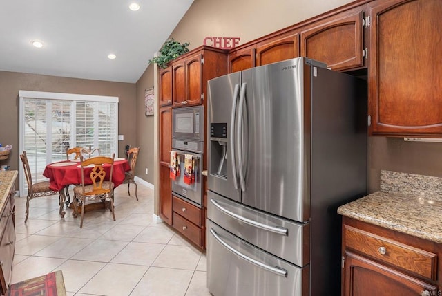 kitchen with vaulted ceiling, light stone counters, recessed lighting, appliances with stainless steel finishes, and light tile patterned flooring