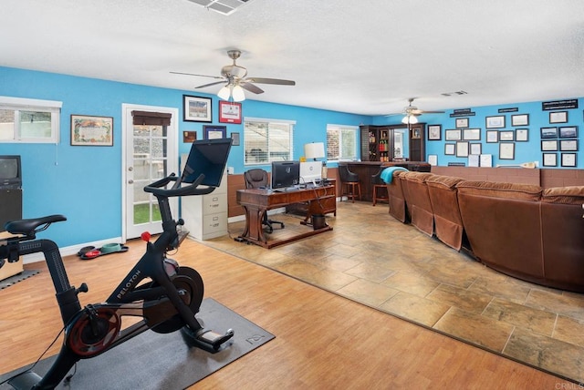 workout area with visible vents, a textured ceiling, wood finished floors, baseboards, and ceiling fan