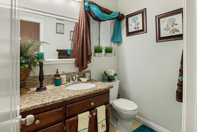 bathroom with vanity, toilet, and baseboards