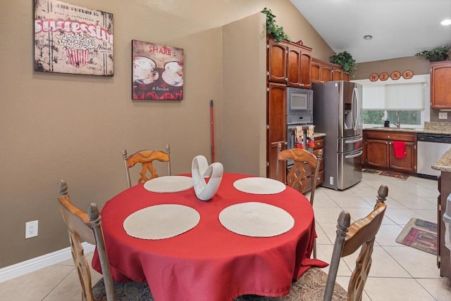 dining area featuring light tile patterned floors, baseboards, and lofted ceiling