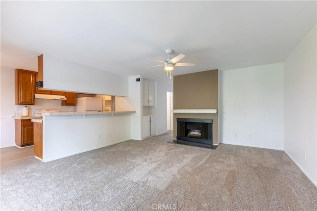 unfurnished living room with light carpet, a fireplace, and ceiling fan