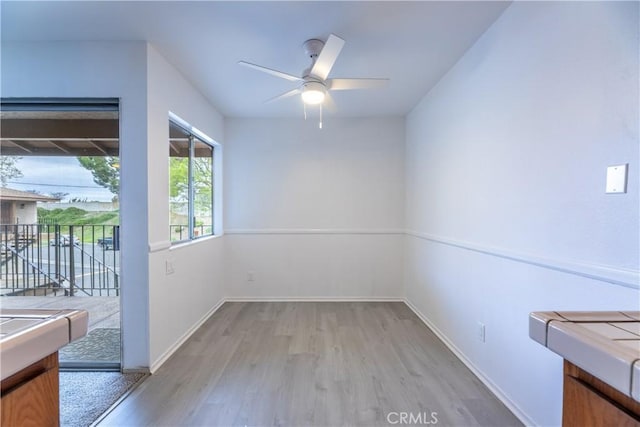 unfurnished room featuring ceiling fan, baseboards, and wood finished floors