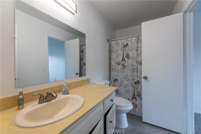 bathroom with curtained shower, toilet, wood finished floors, and vanity