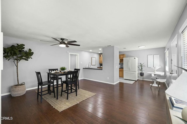 dining room featuring dark wood-style floors, ceiling fan, and baseboards