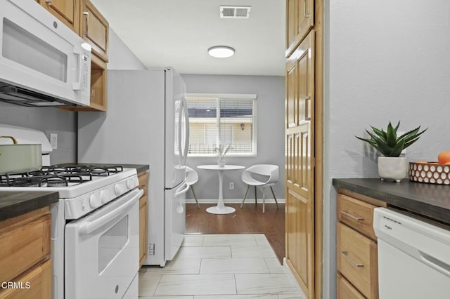 kitchen featuring white appliances, visible vents, baseboards, brown cabinets, and dark countertops