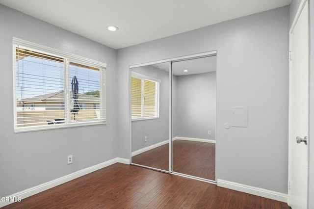 unfurnished bedroom with recessed lighting, a closet, baseboards, and wood finished floors