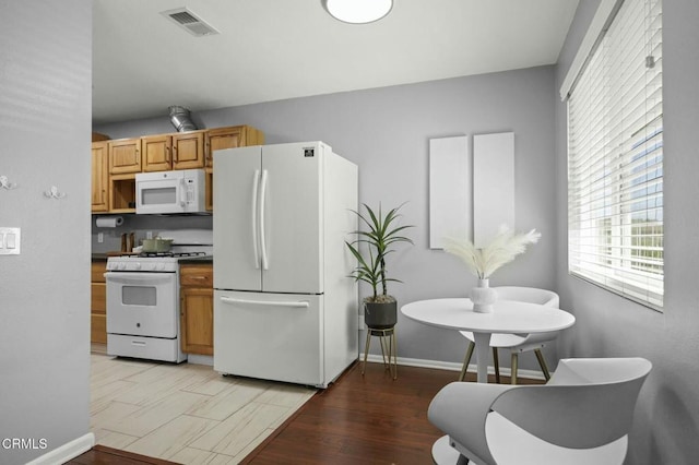 kitchen featuring white appliances, visible vents, baseboards, dark countertops, and light wood-style flooring