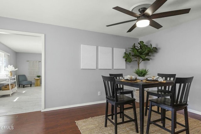 dining area featuring wood finished floors, a ceiling fan, and baseboards