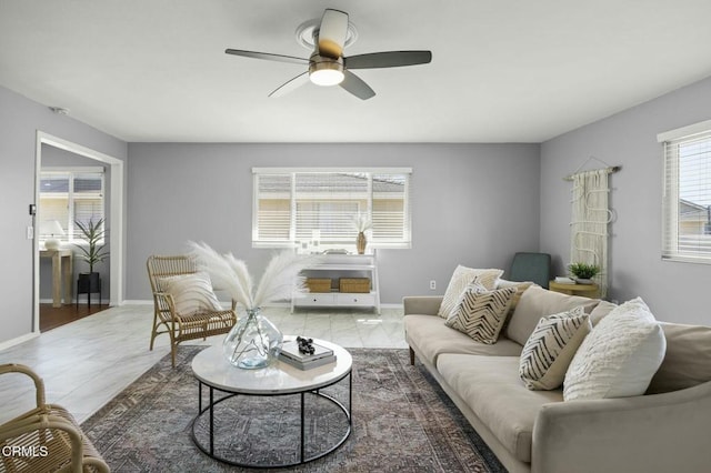 living area with ceiling fan and baseboards