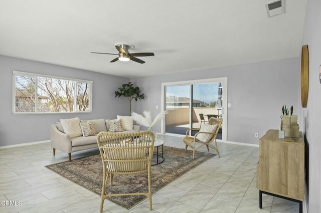 living room featuring baseboards, visible vents, and a ceiling fan