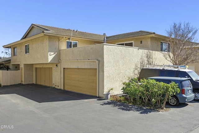 exterior space featuring a garage, fence, and stucco siding