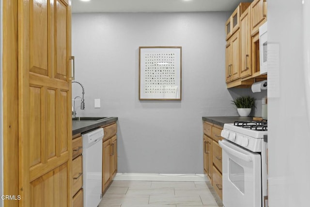 kitchen featuring white appliances, a sink, baseboards, dark countertops, and glass insert cabinets