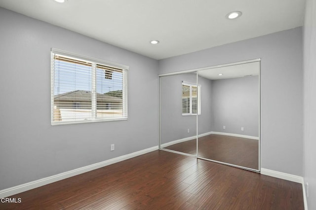 unfurnished bedroom with a closet, baseboards, wood finished floors, and recessed lighting