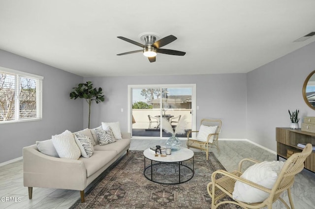 living room featuring a ceiling fan, plenty of natural light, visible vents, and baseboards