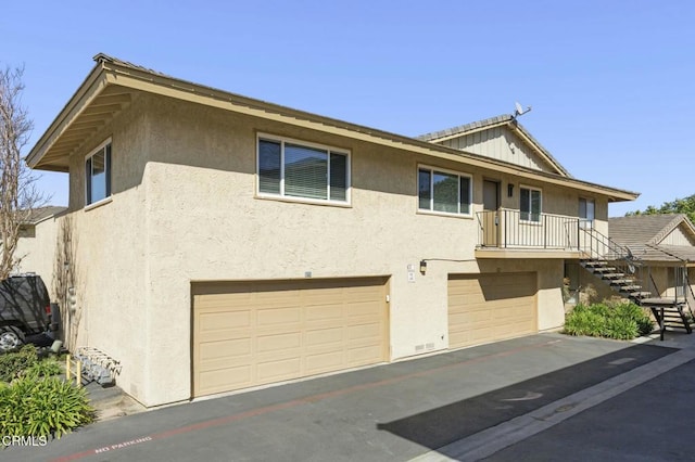 view of front facade with stairs, an attached garage, and stucco siding