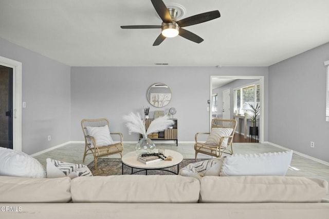 living room featuring visible vents, a ceiling fan, and baseboards