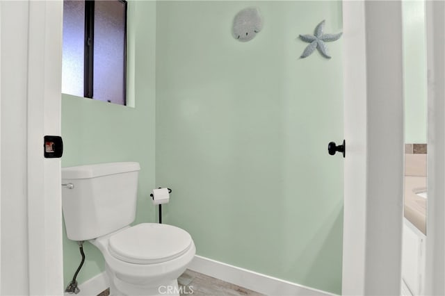 bathroom with baseboards, toilet, and wood finished floors