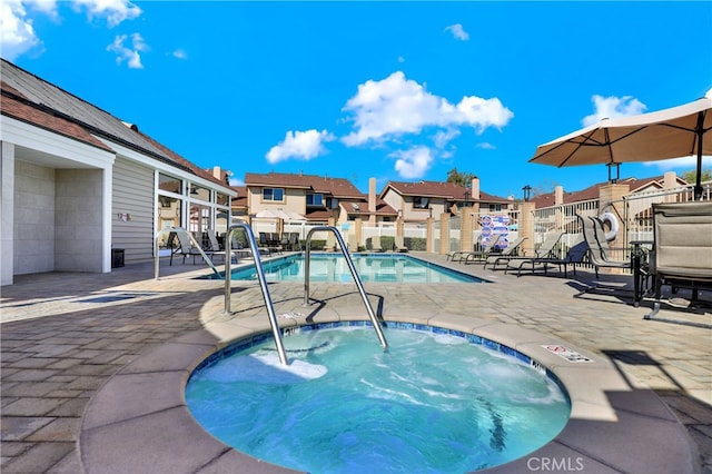 pool with a community hot tub, a patio, fence, and a residential view