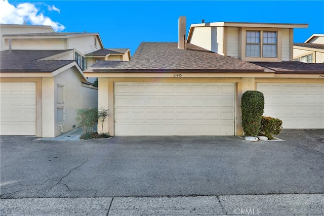 view of front of property featuring a garage, roof with shingles, and stucco siding