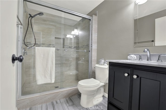 full bathroom with vanity, a shower stall, and toilet