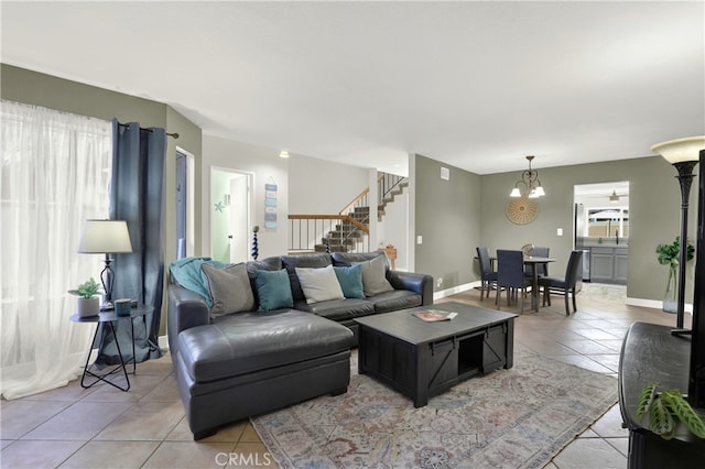 living area featuring light tile patterned floors, baseboards, stairway, and a chandelier