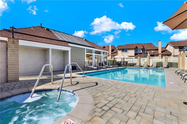 community pool with a residential view, a patio, a hot tub, and fence