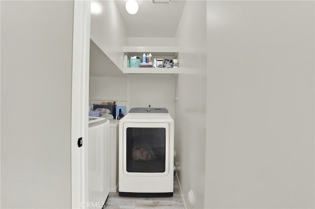 laundry area featuring light wood-type flooring, laundry area, baseboards, and washer and clothes dryer