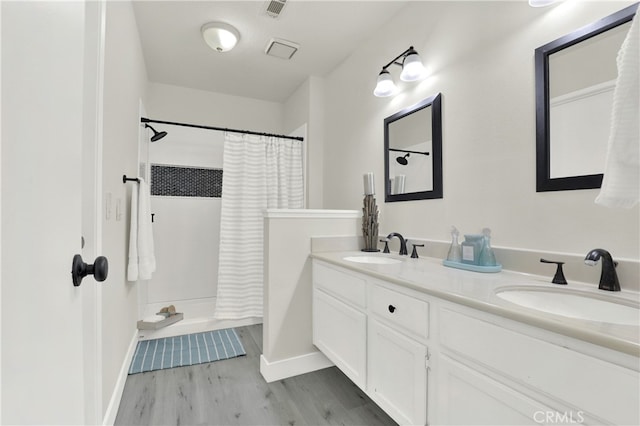 bathroom featuring double vanity, visible vents, a sink, and wood finished floors