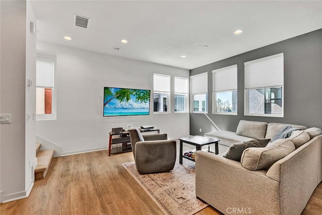 living area with light wood-type flooring, visible vents, baseboards, and recessed lighting