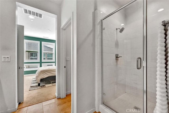 bathroom with ensuite bathroom, tile patterned flooring, visible vents, baseboards, and a stall shower