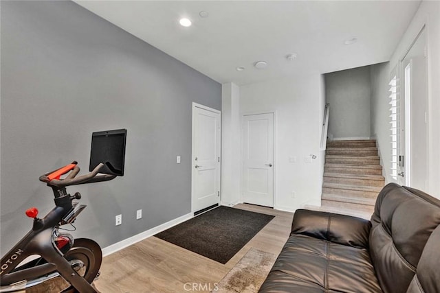 exercise room featuring baseboards, wood finished floors, and recessed lighting