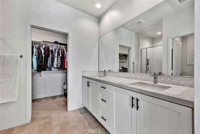 full bath with a sink, visible vents, a spacious closet, a shower stall, and double vanity