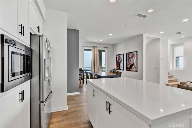 kitchen with appliances with stainless steel finishes, recessed lighting, a kitchen island, and light wood-style flooring