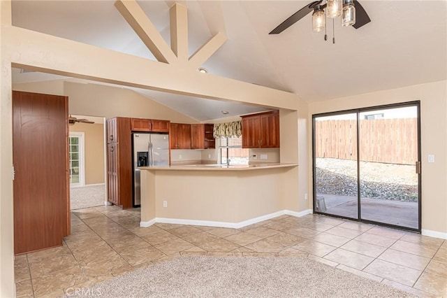 kitchen with lofted ceiling, brown cabinetry, stainless steel refrigerator with ice dispenser, and light countertops