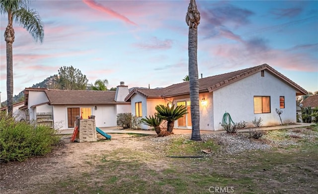 view of front of home featuring a chimney and stucco siding