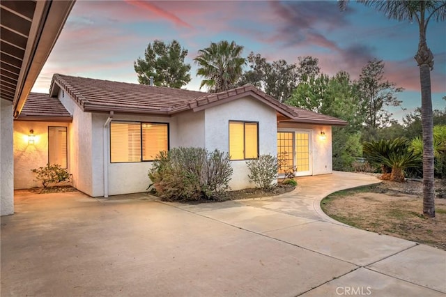 back of house featuring a patio, a tiled roof, and stucco siding